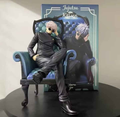 Figura Satoru Gojo Sentado Sillón Azul Jujutsu Kaisen 24cm con traje negro de cuero, gafas redondas y caja oficial
